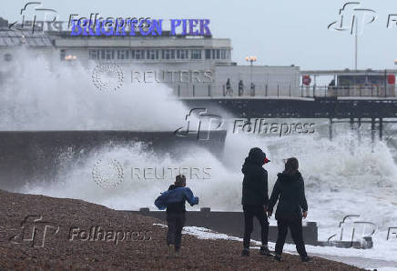 People walk on the beach near Palace Pier as Storm Nelson arrives at Brighton