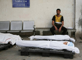 A mourner sits next to the bodies of Palestinians killed in Israeli strikes, in Rafah