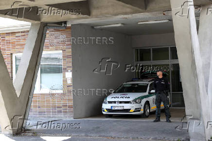 A police officer stands next to a police vehicle parked outside F.D. Roosevelt University Hospital where Slovak Prime Minister Robert Fico was taken after a shooting incident in Handlova, in Banska Bystrica