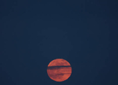 The full moon, also known as the Pink moon, rises in Luka village,