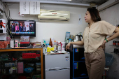 A nail salon shopkeeper watches a live broadcast as Taiwan's new President Lai Ching-te and former President Tsai Ing-wen walk