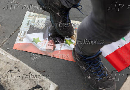 A man walks on a picture of President Bashar al-Assad, in Damascus