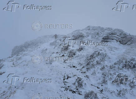 A fell runner makes his way through the snow as he runs up Ullock Pike near Keswick