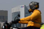 A man rides his motorbike past the Corporate House of Adani Group on the outskirts of Ahmedabad