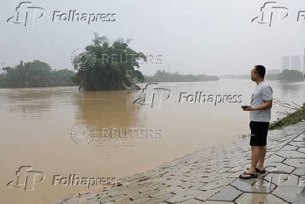 Resident looks on as he stands near a flooded river following heavy rainfall in Qingyuan, Guangdong