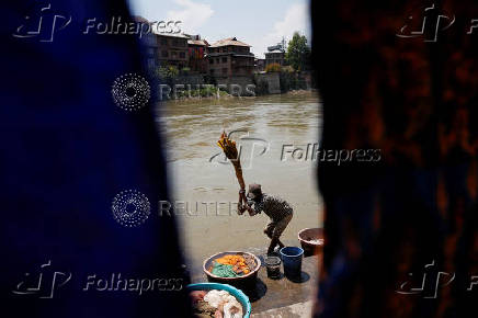 A washerman washes embroidered shawls on the banks of river Jhelum, in Srinagar