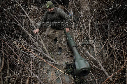 A serviceman prepares a howitzer to fire towards Russian troops at a frontline near the town of Chasiv Yar