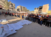 People pray next to the bodies of Palestinians killed in Israeli strikes, amid the Israel-Hamas conflict, in Khan Younis in the southern Gaza Strip