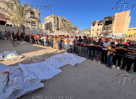 People pray next to the bodies of Palestinians killed in Israeli strikes, amid the Israel-Hamas conflict, in Khan Younis in the southern Gaza Strip