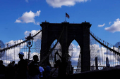 People pose for photographs as other walk on the Brooklyn Bridge in New York City