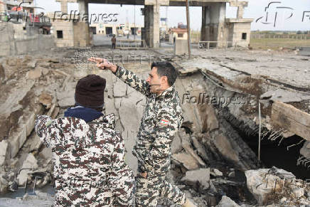 Lebanese military personnel stand near a damaged site at the Lebanese-Syrian border crossing of Arida