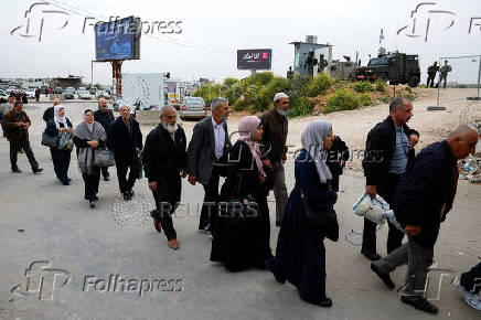 Palestinians walk near an Israeli checkpoint, as they make their way to Jerusalem's Al-Aqsa compound to attend Friday prayers during Ramadan