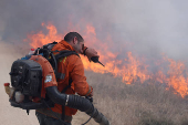 A man attempts to extinguish flames following a rocket attack from Lebanon, in the Israeli-occupied Golan Heights