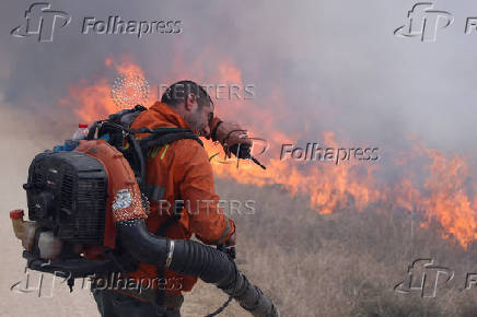 A man attempts to extinguish flames following a rocket attack from Lebanon, in the Israeli-occupied Golan Heights