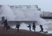People run on the beach near Palace Pier as Storm Nelson arrives at Brighton