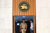 FILE PHOTO: A policeman walks past a logo of the Reserve Bank of India (RBI) inside the RBI headquarters in Mumbai