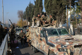 FILE PHOTO: Rebel fighters sit on a vehicle, in Damascus