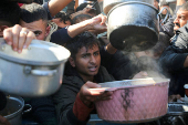 Palestinians gather to receive food cooked by a charity kitchen, in Khan Younis