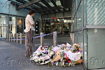 A person looks at floral tributes for victims of the attack left at the entrance to Westfield Bondi Junction shopping centre in Sydney