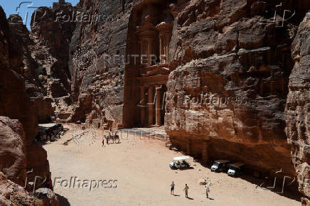 Visitors stand in front of the treasury site in the ancient city of Petra