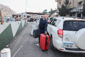 A man with his bags walks after crossing from Syria into Lebanon, after Syrian rebels announced that they have ousted President Bashar al-Assad, at Masnaa Border Crossing