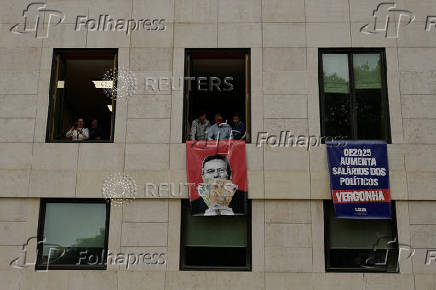 Far-right political party Chega expose banners on the facade of the Portuguese parliament against the wage reinstatement for politicians after the cuts imposed by the Troika, during the debate and vote of the 2025 budget bill on final reading, in Lisbon