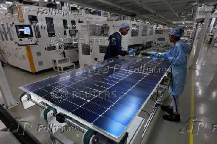 Workers assemble Photovoltaic Modules at the plant of Adani Green Energy Ltd (AGEL) in Mundra