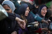 Palestinians gather to receive food cooked by a charity kitchen, in Khan Younis