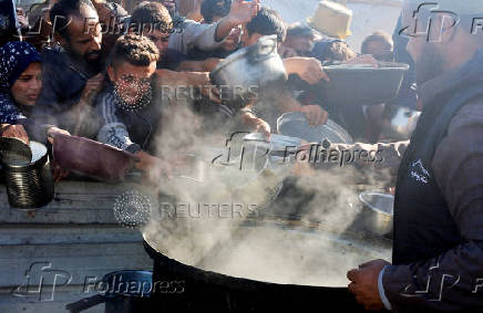 Palestinians gather to receive food cooked by a charity kitchen, amid a hunger crisis, in Khan Younis