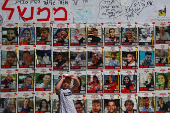 People walk past posters in support of hostages who were kidnapped during the deadly October 7 attack, in Tel Aviv