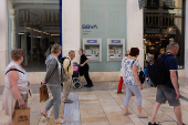 People walk past a BBVA bank branch office in Malaga