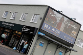 People stand near a sign encouraging people to vote, in Greystones