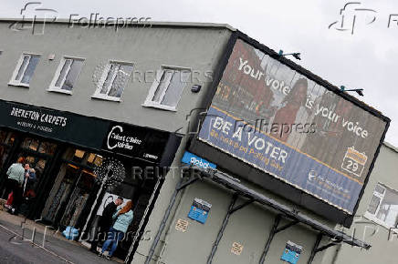 People stand near a sign encouraging people to vote, in Greystones