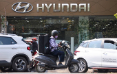 FILE PHOTO: A man rides a scooter past a Hyundai automobile showroom in Mumbai