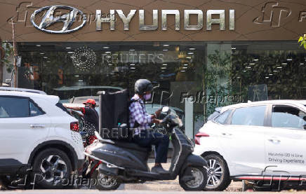 FILE PHOTO: A man rides a scooter past a Hyundai automobile showroom in Mumbai