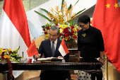 Chinese Foreign Minister Wang Yi signs the guest book as Indonesian Foreign Minister Retno Marsudi looks on in Jakarta