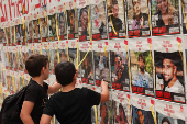 Children look at posters with pictures of hostages who were kidnapped during the deadly October 7 attack on Israel by Hamas, in Tel Aviv