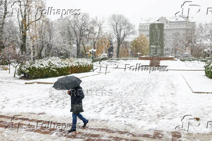 Man with an umbrella walks in a park during a snowfall in Kyiv