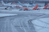 Staff use a tractor to help clear snow from around aircraft after overnight snowfall caused the temporary closure of Manchester Airport, in Manchester