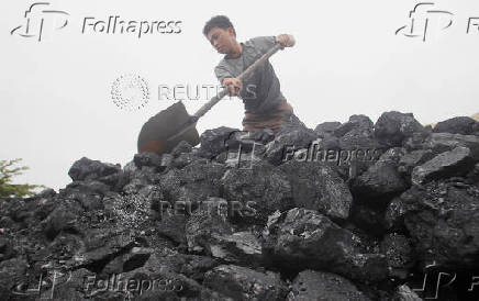 FILE PHOTO: A worker shovels coal as he loads a truck at a coal port in Hanoi
