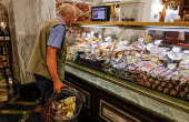 An elderly man looks at a counter with sausages in a supermarket in Moscow