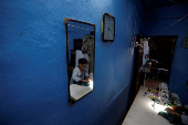 Kavita Rajkumar Pal works on her sewing machine inside her home after it was painted with solar reflective paint in a slum area in Ahmedabad