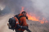 A man attempts to extinguish flames following a rocket attack from Lebanon, in the Israeli-occupied Golan Heights