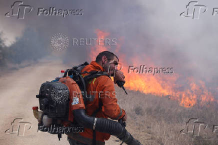 A man attempts to extinguish flames following a rocket attack from Lebanon, in the Israeli-occupied Golan Heights