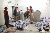 Rescue workers stand amid the bodies at a hospital morgue, after a bomb blast at a railway station in Quetta