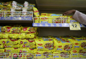 FILE PHOTO: A worker arranges packets of Nestle's Maggi noodles next to Reliance's Snac tac noodles on a shelf inside a Reliance supermarket in Mumbai