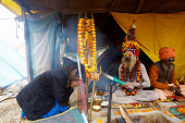 A Naga Sadhu or Hindu holy man blesses a devotee inside his tent during the 