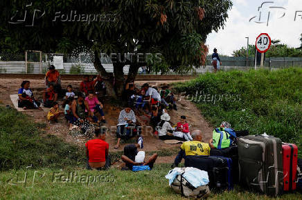 Venezuelans sit under a tree as they wait to enter a shelter after leaving Venezuela, near the border in Pacaraima