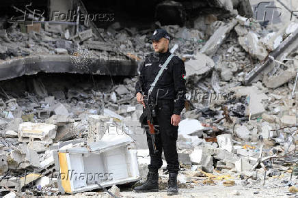 Palestinian Hamas policemen keep guard at their destroyed headquarters in Gaza City