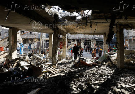 Palestinians inspect the site of an Israeli strike on a house, in Rafah